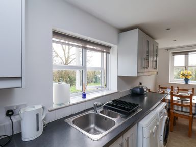 A kitchen with a sink, countertop appliances, and a dining table with chairs at The Barn - Poplar Farm in Lower Dunsforth near Boroughbridge