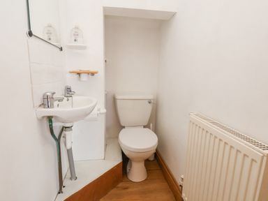 A small bathroom with a toilet sink a mirror and a radiator at The Barn - Poplar Farm in Lower Dunsforth near Boroughbridge