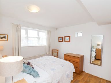 A bedroom with a bed pillows lamp dresser chair wall mirror and paintings at The Barn - Poplar Farm in Lower Dunsforth near Boroughbridge