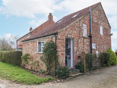 A brick house with a tiled roof and small garden along a gravel path at The Barn - Poplar Farm in Lower Dunsforth near Boroughbridge