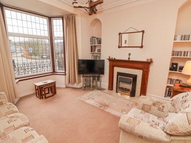 A living room with a fireplace television and a large bay window at Glan Yr Afon in Ystradgynlais