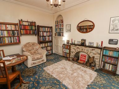 A room with bookshelves an armchair a table a fireplace and a mirror at Glan Yr Afon in Ystradgynlais