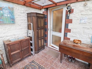 A room with wooden cabinets a folding ladder a rug and a door at Glan Yr Afon in Ystradgynlais
