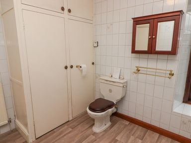 A bathroom with a toilet, wall-mounted cabinet with mirrors, towel rack, and built-in cupboard at Glan Yr Afon in Ystradgynlais