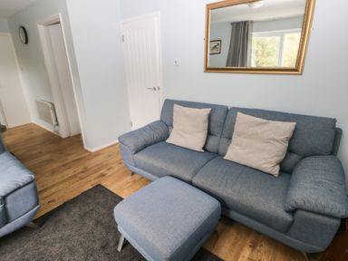 A living room with blue couches a gray rug and a mirror on the wall at Kittiwake Apartment 22 in Little Haven near Broad Haven