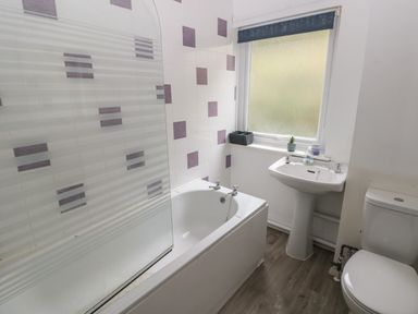 A bathroom with a bathtub shower screen sink toilet and a window with a blind at Kittiwake Apartment 22 Little Haven near Broad Haven