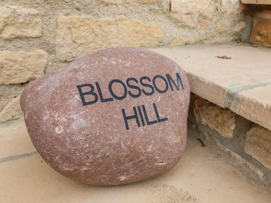 A stone with the words Blossom Hill engraved placed on a tiled step near a stone wall at Blossom Hill near Witney