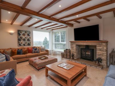 A living room with wooden ceiling beams a stone fireplace and a large corner sofa at Blossom Hill near Witney