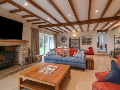 A living room with wooden beams on the ceiling and a stone fireplace at Blossom Hill near Witney
