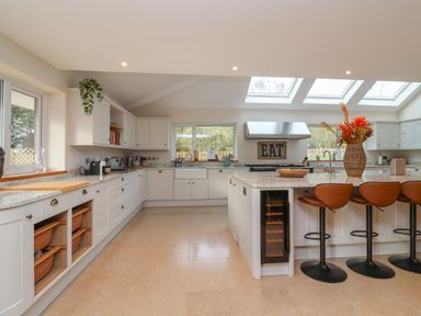 A kitchen with white cabinets a large island with barstools and skylights at Blossom Hill near Witney