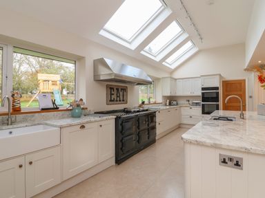 A kitchen with white cabinets a black stove and skylights at Blossom Hill near Witney