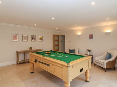 A room with a pool table two chairs a small table with flowers and framed pictures on the wall at Blossom Hill near Witney