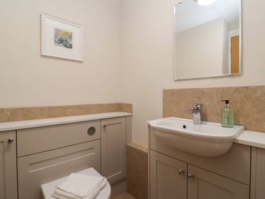 A bathroom with a sink a mirror a toilet with a towel on top and a framed picture on the wall at Blossom Hill near Witney