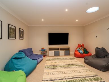 A room with bean bag chairs a television on a stand toys and framed pictures on the wall at Blossom Hill near Witney
