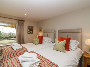 A bedroom with two beds with pillows and folded towels by a window at Blossom Hill near Witney