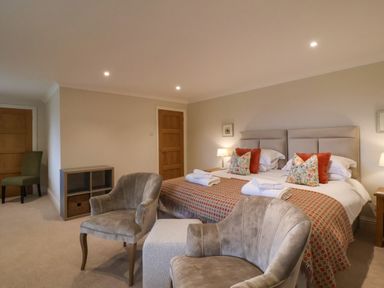 A bedroom with a double bed two armchairs a small table and wooden doors at Blossom Hill near Witney