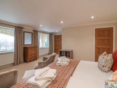 A bedroom with a bed with folded towels two windows and a wooden dresser at Blossom Hill near Witney