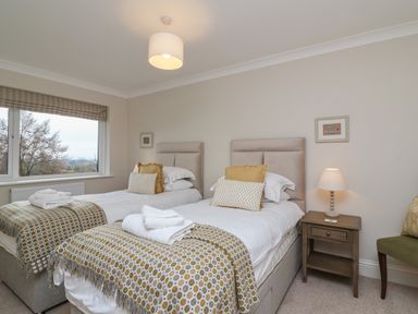A bedroom with two single beds bedside table with lamp and a window at Blossom Hill near Witney