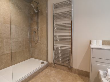 A bathroom with a walk-in shower a heated towel rail and a countertop with two rolls of toilet paper at Blossom Hill near Witney