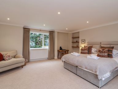 A bedroom with a large bed sofa desk and window with curtains at Blossom Hill near Witney