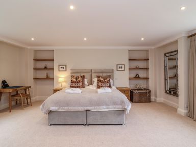 A bedroom with a bed two bedside tables built in shelves a desk and a large mirror at Blossom Hill near Witney