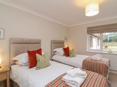 A bedroom with two single beds with pillows and folded towels near a window at Blossom Hill near Witney