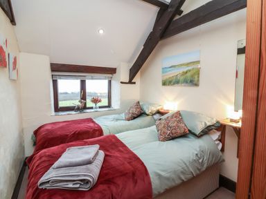 A bedroom with two single beds and a window with a view at Badgers Sett in Stibb near Kilkhampton