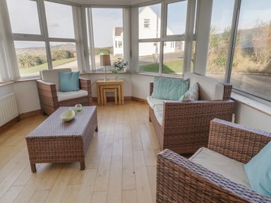 A seating area with woven chairs and a table by large windows at Horn Head View in Carrigart County Donegal
