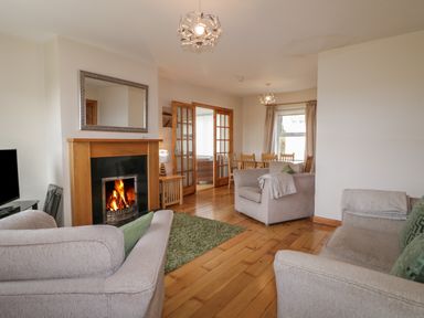 A living room with beige sofas a fireplace and dining table at Horn Head View in Carrigart County Donegal