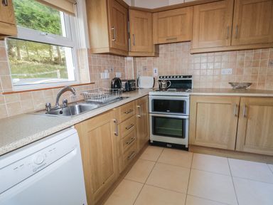 A kitchen with wooden cabinets a stove a sink and a dishwasher at Horn Head View in Carrigart County Donegal