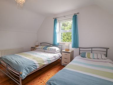 A bedroom with two single beds a nightstand with a lamp and blue curtains at Horn Head View in Carrigart County Donegal