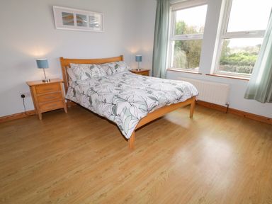 A bedroom with a wooden bed and bedside tables next to windows at Horn Head View in Carrigart County Donegal