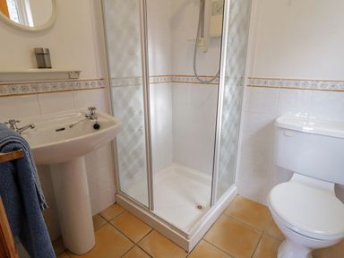 A bathroom with a shower cubicle a toilet and a pedestal sink with a mirror at Horn Head View in Carrigart County Donegal