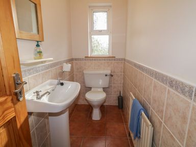 A small bathroom with a toilet sink and window at Horn Head View in Carrigart County Donegal