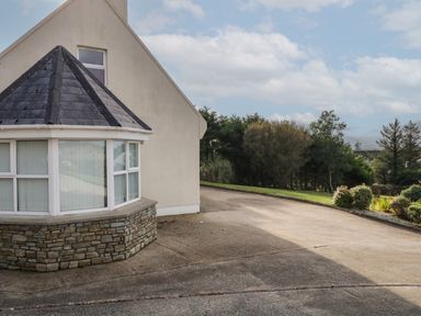 A driveway beside a house with stone and windowed extension and garden with trees at Horn Head View in Carrigart County Donegal