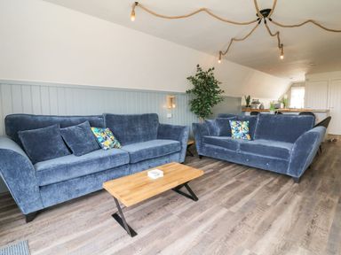 A living room with two blue sofas and a wooden coffee table at La Bella Vista in Kilkhampton