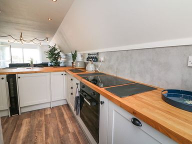 A modern kitchen with wooden countertops white cabinets black stove and oven and plants near a window at La Bella Vista in Kilkhampton