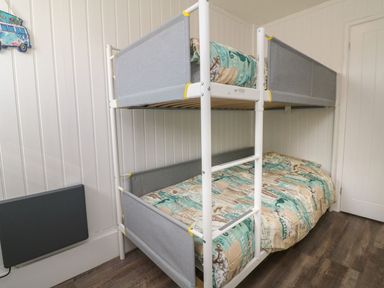 A bedroom with a white bunk bed and patterned bedding at La Bella Vista in Kilkhampton
