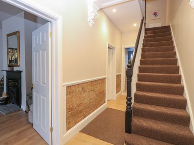 A hallway with carpeted stairs and exposed brick lower walls at Grosvenor House in Kirkley Rise