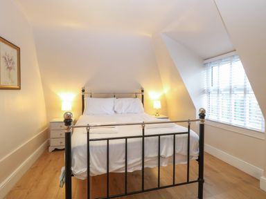 A bedroom with a metal frame bed two bedside tables with lamps a window with blinds and a framed picture on the wall at Grosvenor House in Kirkley Rise