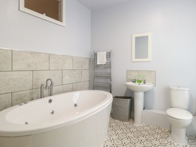 A bathroom with a bathtub a sink a toilet a towel rack and a waste bin at Grosvenor House in Kirkley Rise