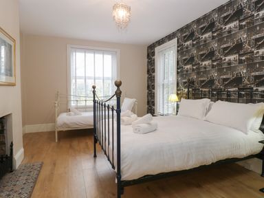 A bedroom with two metal frame beds and patterned wallpaper at Grosvenor House in Kirkley Rise