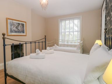 A bedroom with a large bed and a single bed with white linens and rolled towels on the beds at Grosvenor House in Kirkley Rise