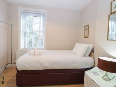 A bedroom with a single bed white bedding a window and a bedside table with a lamp at Grosvenor House in Kirkley Rise