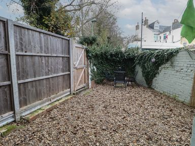 A fenced outdoor yard with gravel ground and a table with chairs at Grosvenor House in Kirkley Rise