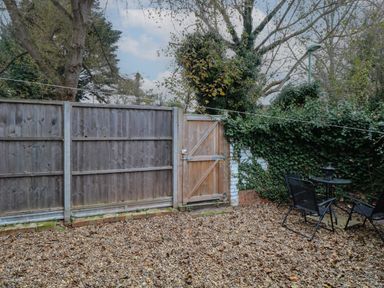 An outdoor area with a wooden gate a gravel ground a small table with two chairs and a fence covered with ivy at Grosvenor House in Kirkley Rise