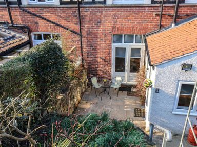 A small patio with a round table and two chairs outside a brick building at Trackside in Ruswarp