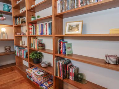 Wooden shelves with books plants board games and decorative items in a room at Trackside Ruswarp