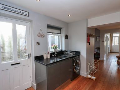 A kitchen area with a sink washing machine and countertop next to a white door at Trackside in Ruswarp
