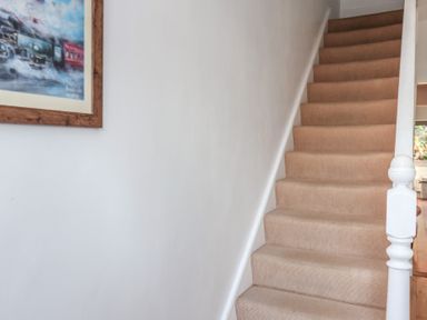 A carpeted staircase with white walls and a framed picture on the left at Trackside Ruswarp